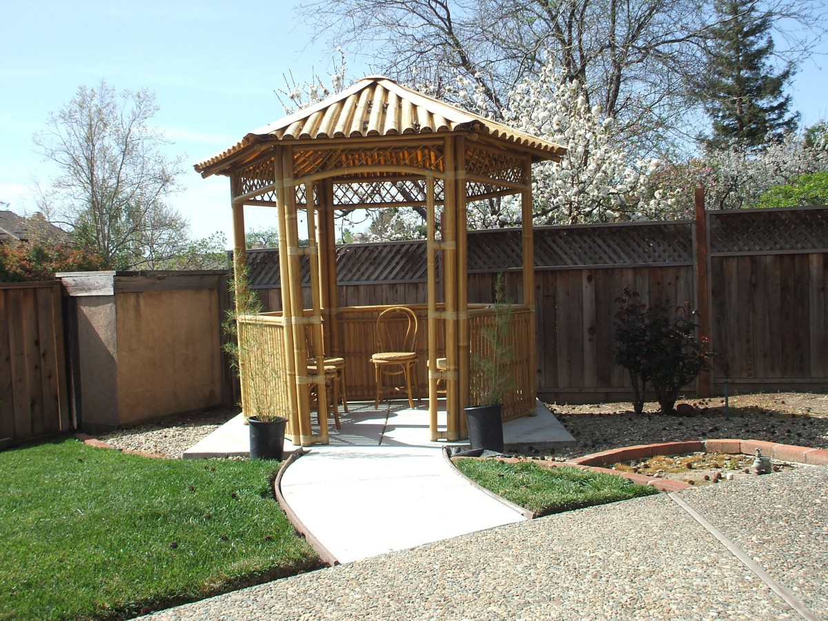 A wooden gazebo with a pathway in a landscaped garden setting.