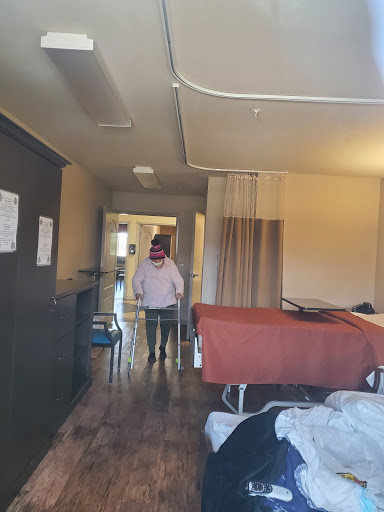 A view of a hospital room with a patient walking in the corridor.
