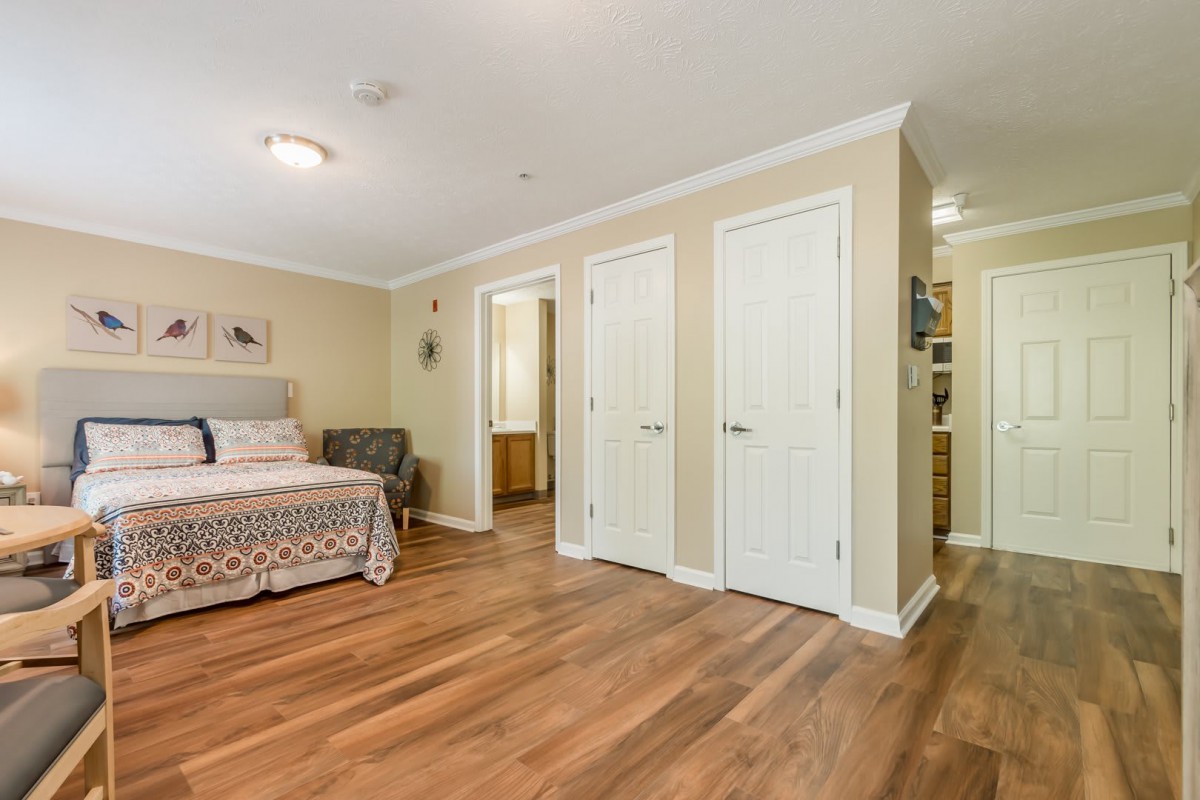 Spacious bedroom with hardwood floors, featuring a bed, seating area, and multiple doors.