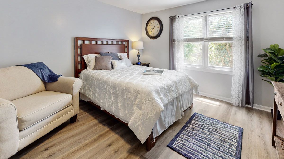 A cozy bedroom with a comfortable bed, a large window, and modern decor.