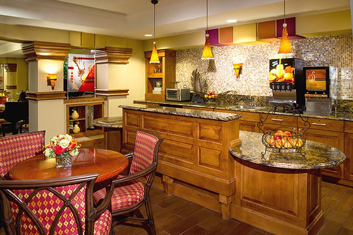A warm and inviting kitchen with wooden cabinetry, granite countertops, and a small dining area.