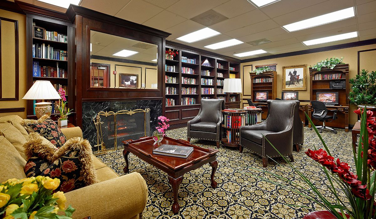 A cozy library with elegant bookshelves, a fireplace, and comfortable seating.