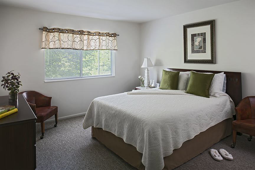 A cozy bedroom with a neatly made bed, a window letting in natural light, and simple decor.