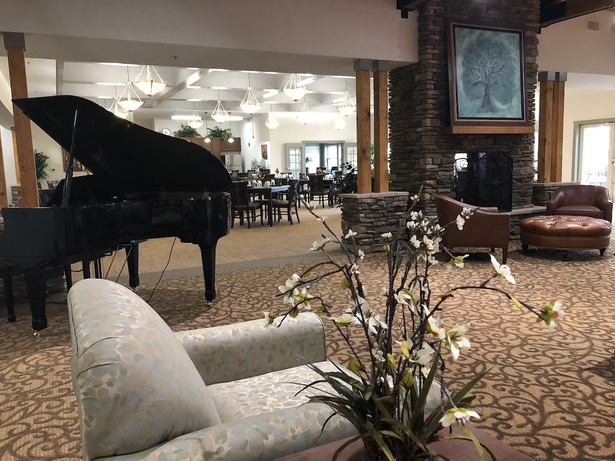 A cozy lounge area featuring a grand piano, comfortable seating, and a fireplace with elegant decor.