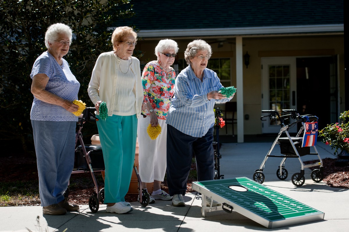 A group of elderly women enjoying a game of cornhole outdoors.