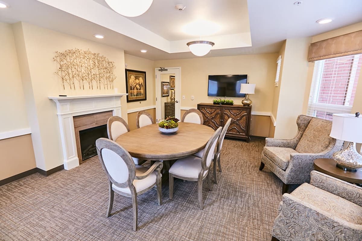 A cozy dining room with a round table, elegant chairs, and a fireplace, adorned with stylish decor and art.