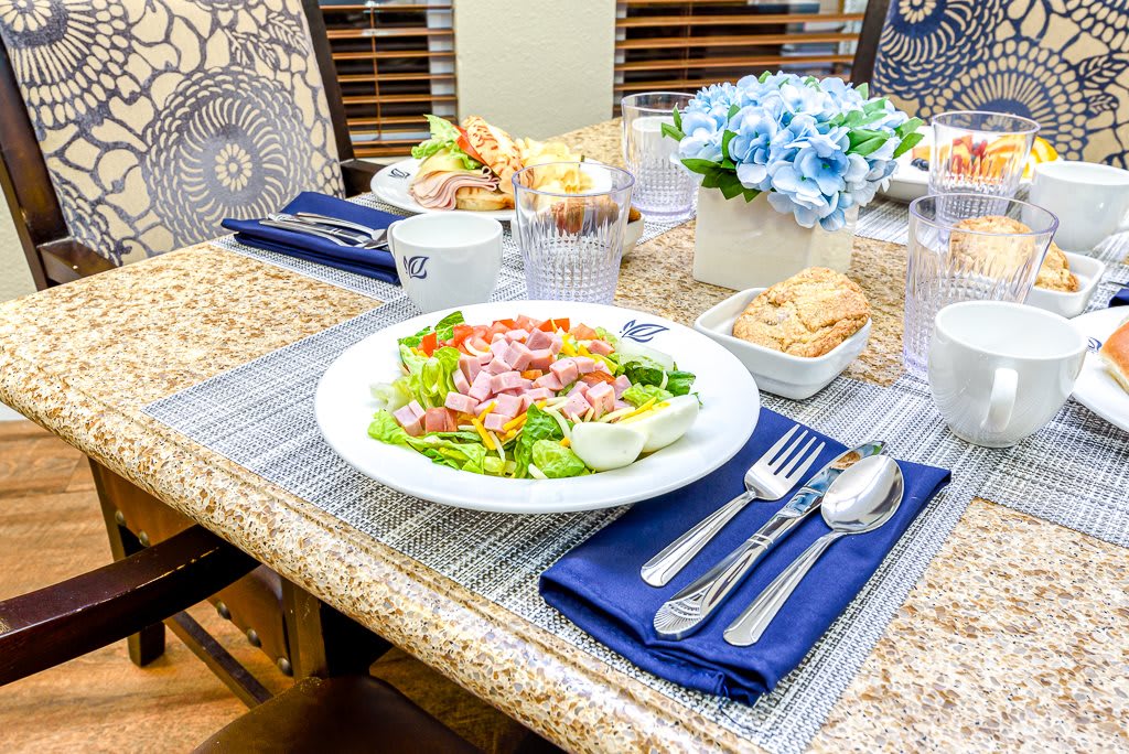 A beautifully set dining table with a fresh salad and elegant tableware.