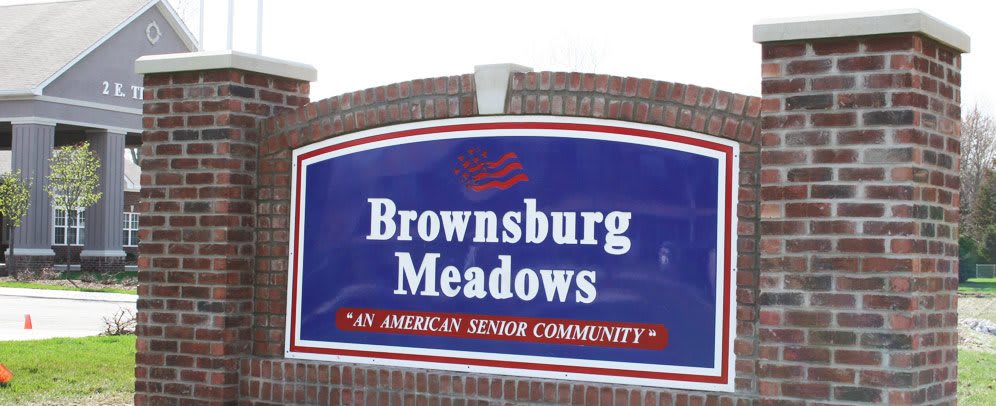 A sign for Brownsburg Meadows, an American senior community, displayed on a brick structure.