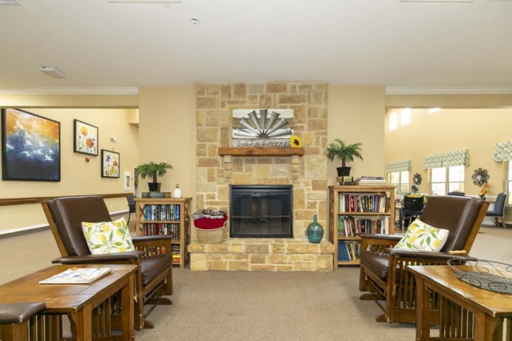 A cozy living room with a stone fireplace, surrounded by bookshelves and comfortable seating.