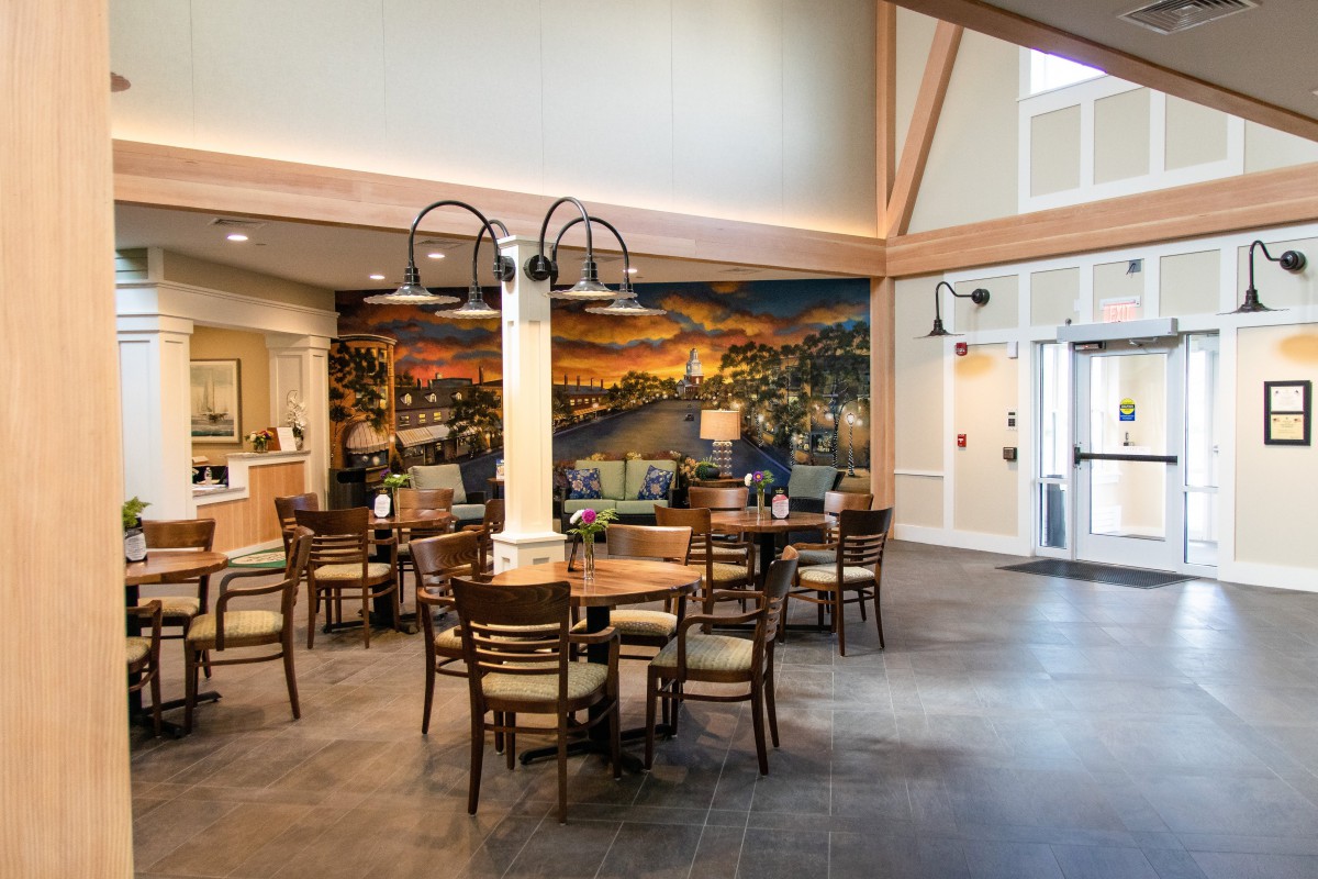 A cozy dining area with wooden tables and chairs, featuring a large mural on the wall.