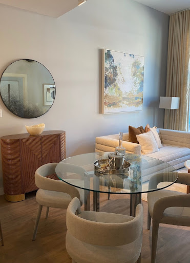 A stylish and modern living room featuring a glass dining table, comfortable seating, and elegant artwork.