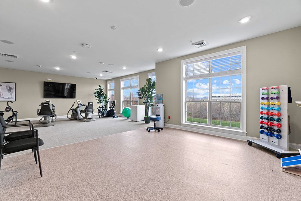A spacious and well-lit gym with exercise equipment including treadmills and stationary bikes.