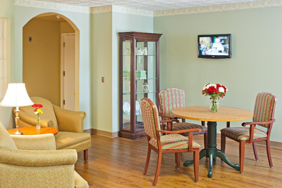 A cozy living room with a table, chairs, sofa, and a wall-mounted TV.
