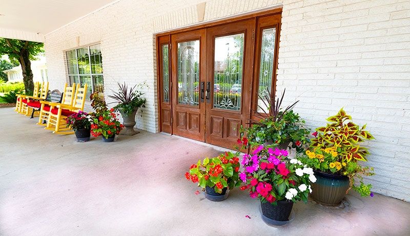 A welcoming front porch adorned with vibrant potted flowers and a wooden double door.