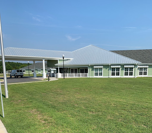 A modern building with a large green lawn under a clear blue sky.