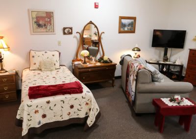A cozy bedroom with a bed, sofa, and vintage furniture.