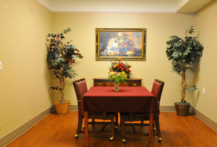 A cozy dining area with a table set for four, adorned with flowers and surrounded by decorative plants.