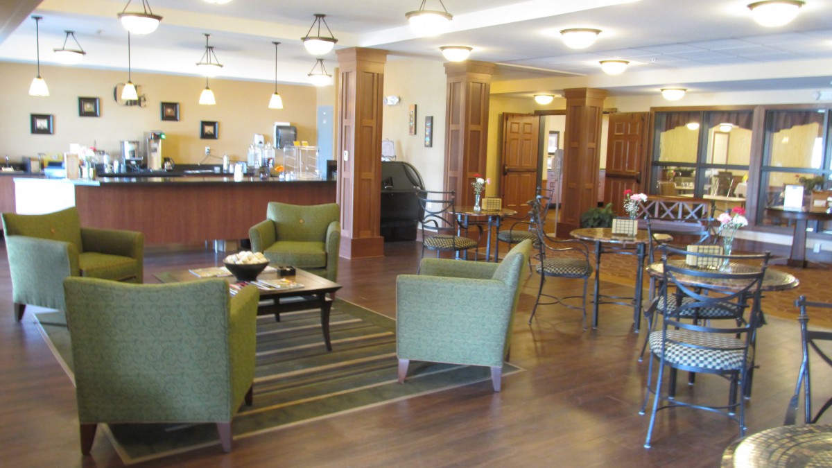 A modern and cozy cafe with green chairs and wooden tables.