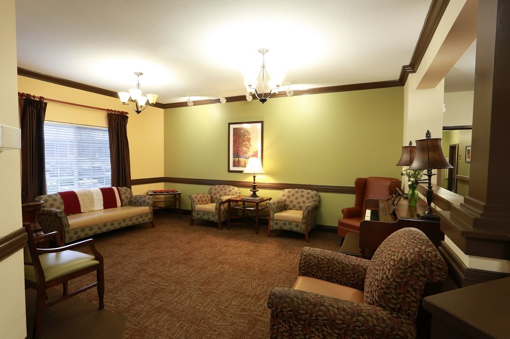 A cozy living room with sofas and armchairs, decorated with a chandelier and wall art.