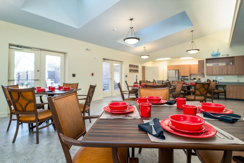 A modern dining area with neatly arranged wooden tables and red tableware.
