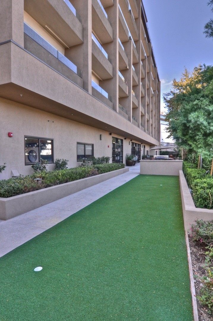 A modern building with well-maintained landscaping and a green lawn area.