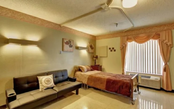 Cozy bedroom with a bed and sofa, featuring warm lighting and inviting decor.