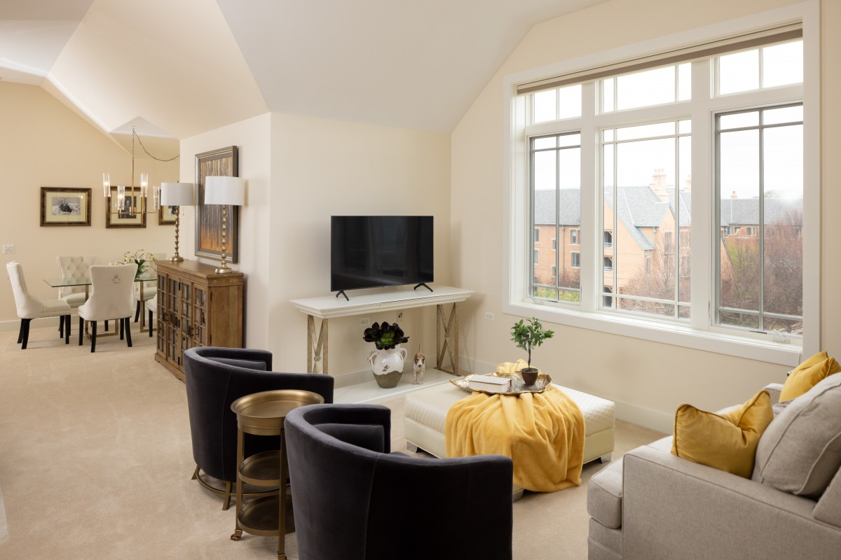 A modern living room with sleek furniture and a large window, featuring a TV and stylish decor.