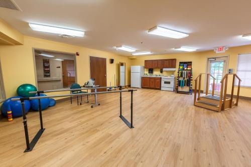 A spacious and well-lit rehabilitation room featuring a kitchenette and various furniture arrangements.