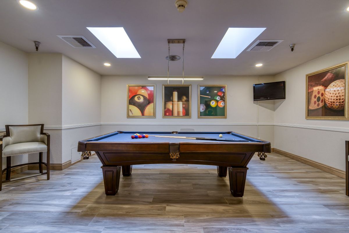 A well-lit game room featuring a pool table and artwork on the walls.