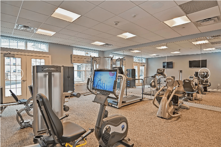 A modern gym with various exercise equipment including treadmills and stationary bikes.
