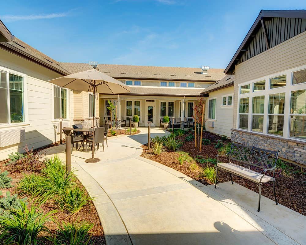 A sunny courtyard with outdoor seating and landscaped pathways in a residential setting.