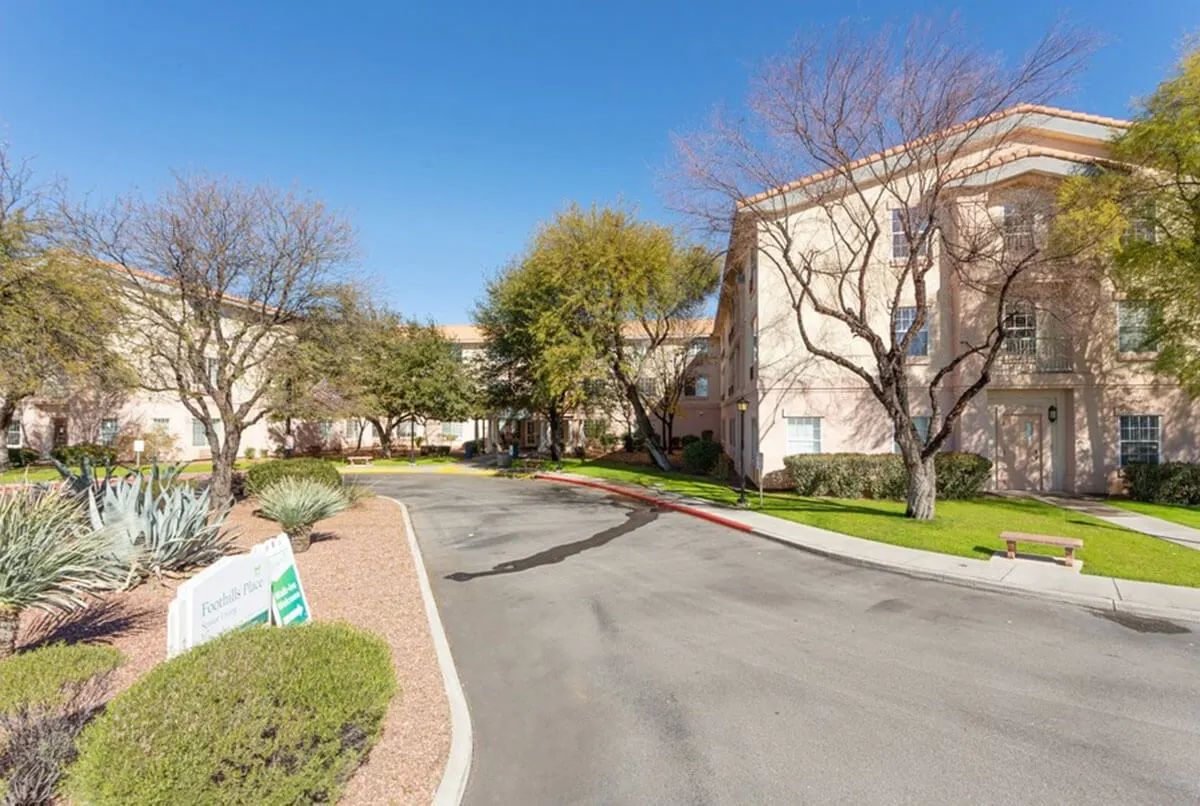 A quiet road curves through a landscaped area with trees and buildings on a clear day.