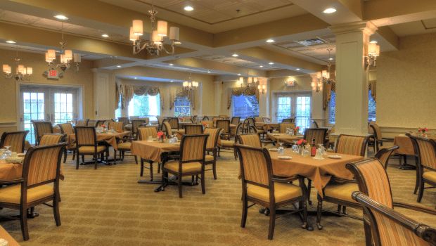 Elegant dining area with neatly arranged tables and chairs under chandeliers.