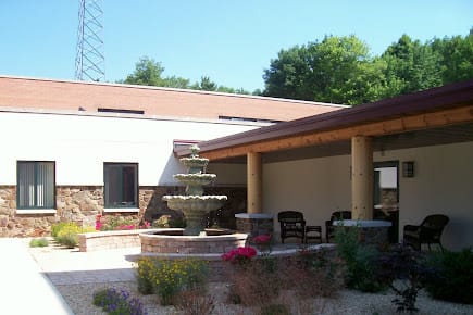 A serene outdoor patio area featuring a multi-tiered fountain surrounded by greenery and seating.