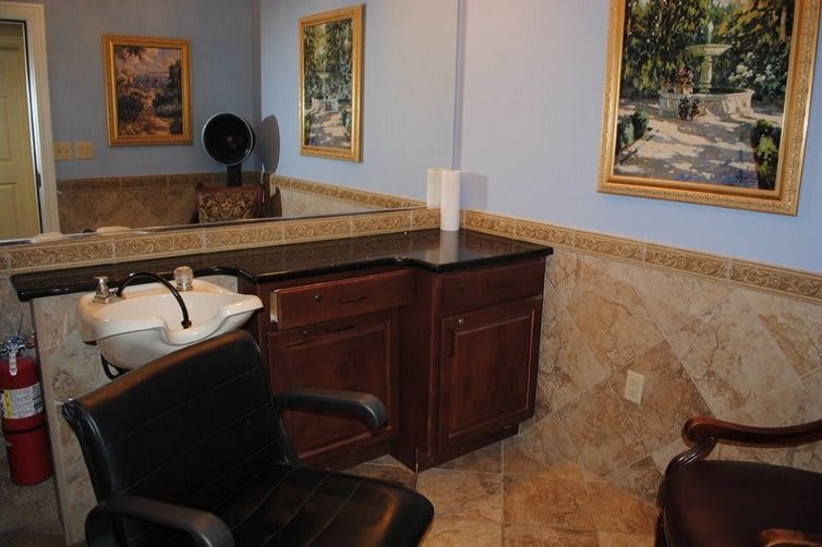 Interior view of a barber shop with a salon chair, sink, mirror, and wall paintings.