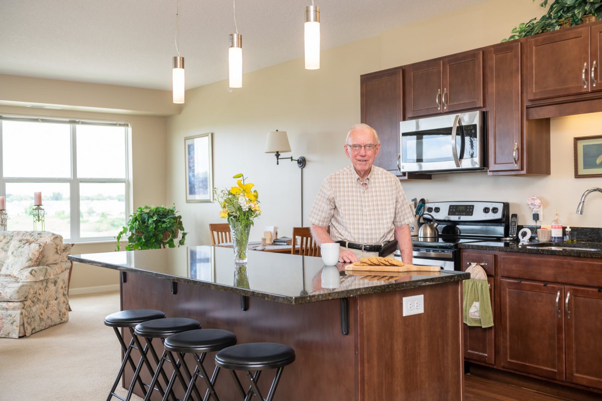 A man stands in a modern kitchen with a large countertop, decorated with flowers.