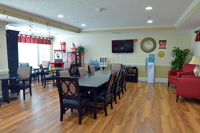 A spacious dining area with a large table and several chairs, featuring a television and modern interior decor.