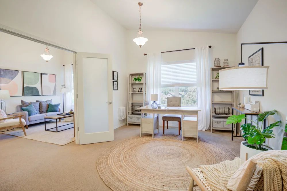 A bright and airy home office with a large desk, comfortable chairs, and ample natural light.