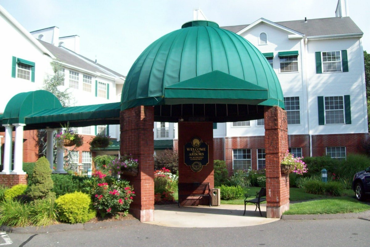 Entrance of a hotel featuring a green dome and brick pillars surrounded by landscaping.
