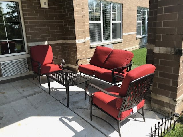 Outdoor patio set with red cushioned chairs and a table.