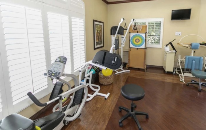A home gym setup featuring various exercise equipment and a wall target for practice.