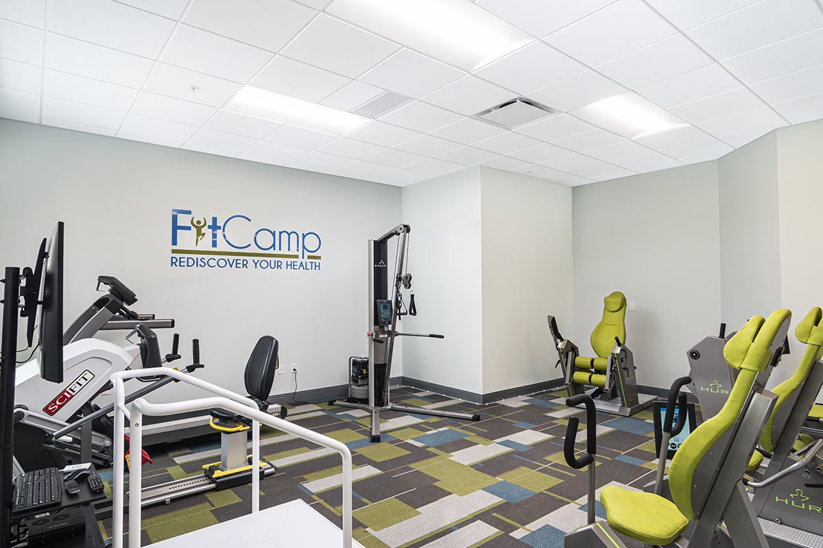 A modern fitness center equipped with various exercise machines and a colorful floor design.