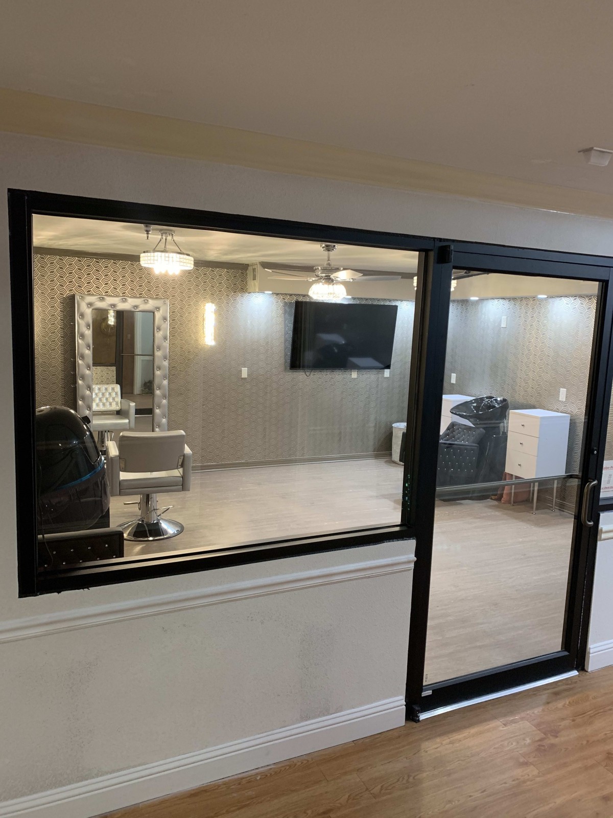A modern beauty salon interior featuring a styling station with a mirror, chair, TV, and sleek lighting.