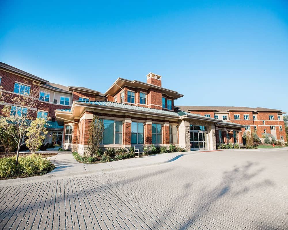 A modern brick residential building with large windows and a spacious driveway.