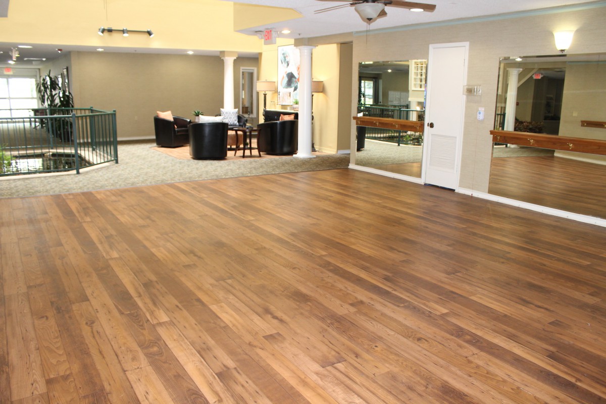 A spacious indoor room with wooden flooring and various seating areas.