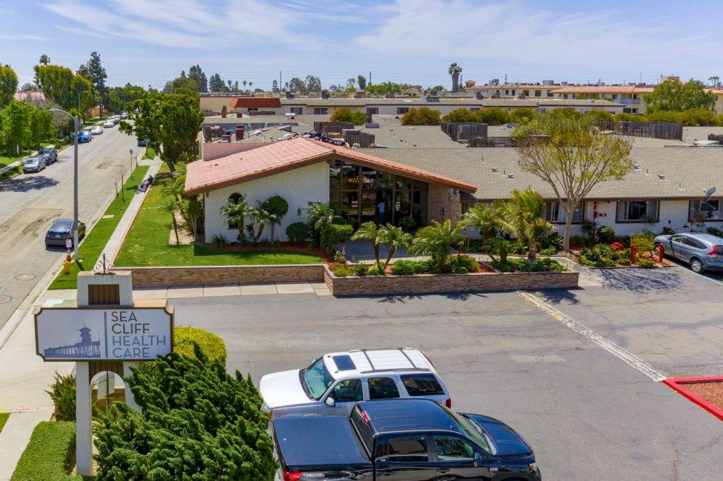 A suburban residential building with a parking lot in the foreground and clear skies.