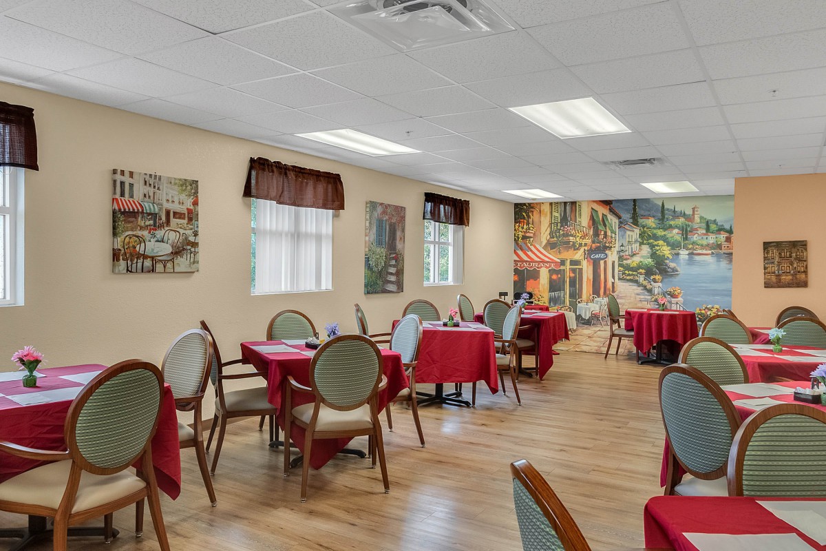 An elegant dining area with red tablecloths and artwork on the walls.