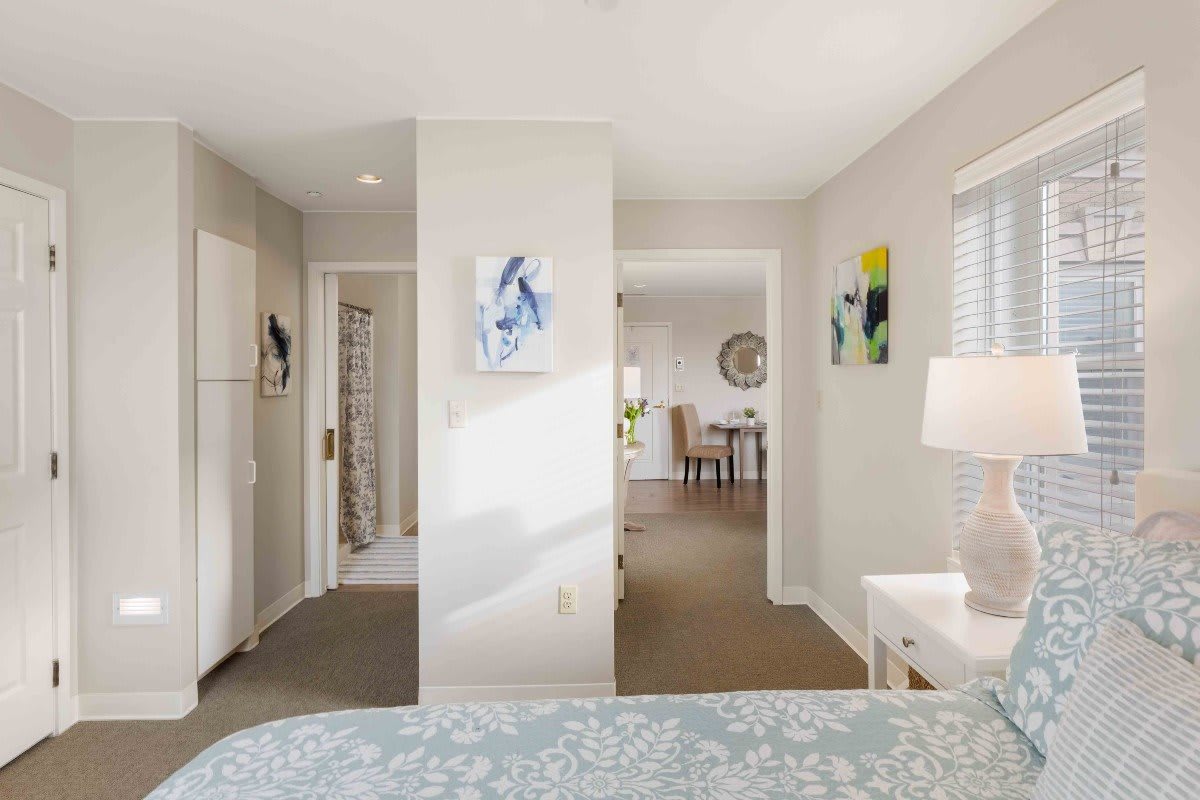 A cozy bedroom with soft lighting and modern decor, featuring a view into an adjoining room.