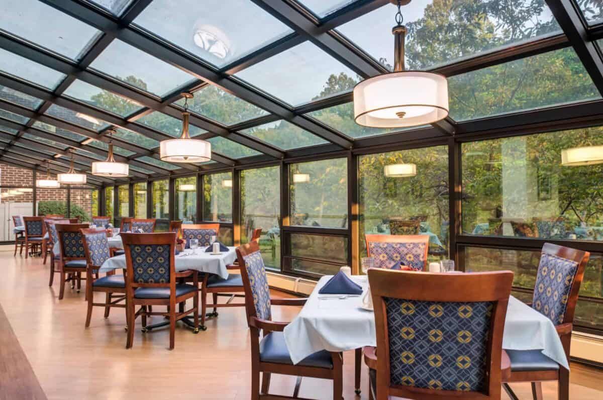 A cozy restaurant dining area with a glass roof, offering a scenic nature view.