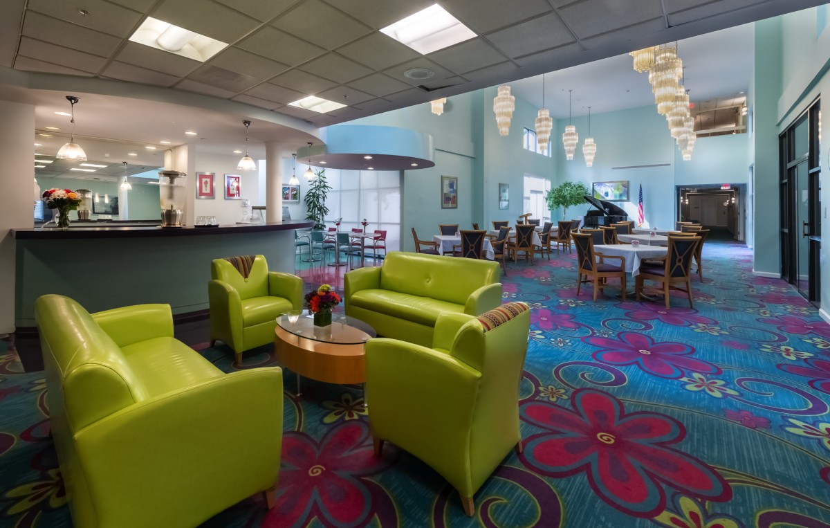 A modern lobby area with vibrant green seating and a colorful floral carpet design.